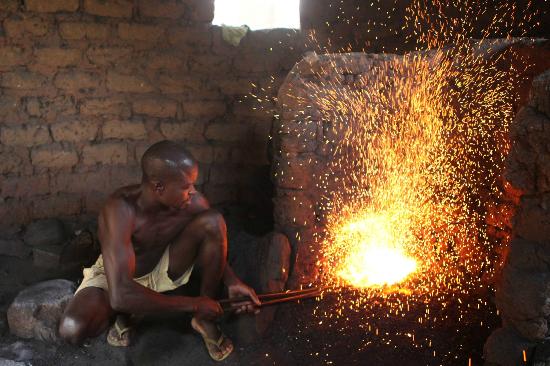 Traditional blacksmith forging iron in Bughungu